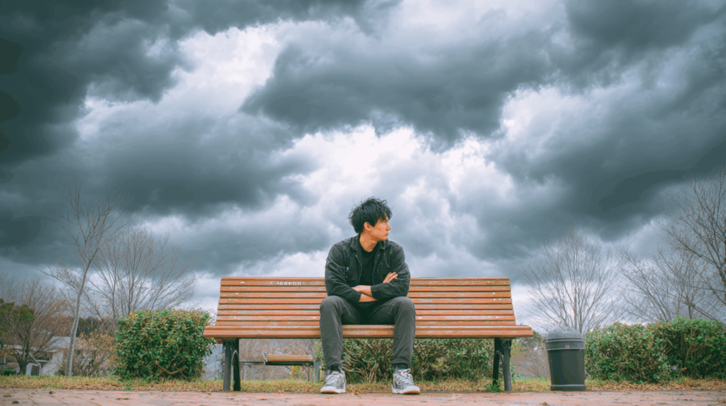 曇り空とベンチに座る男性